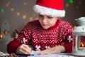 Christmas child writing letter to Santa Claus letter in red hat Royalty Free Stock Photo