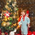Christmas childs in snow. Happy little boy by the Christmas tree. Winter, holidays, family concept.