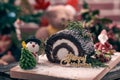 Christmas chocolate roll cake placing together with snow man, Santa Claus sugar, Christmas tree and blue burry Royalty Free Stock Photo