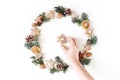 Christmas circle floral composition with womans hand holding cookie. Wreath of fir tree branches, pine cones