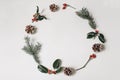 Christmas circle floral composition. Wreath of holly berry, spruce tree branches, pine cones and red rose hips isolated