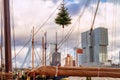 Christmas cityscape - view of the skyscrapers of district Feijenoord through the rigging of the moored sailboat with Christmas tre
