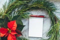 Christmas closeup mockup with poinsettia, pine wreath, notebook, with copy place. Cozy background Royalty Free Stock Photo