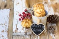 Christmas coconut macaroons with holly berries and pine cones on white wood