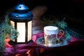 Christmas coffee cup and bright light glowing lantern, green fir tree branches. Royalty Free Stock Photo