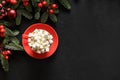 Christmas coffee, holiday red decorations, evergreen nobilis branches and balls on black.