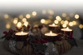 Christmas is coming with Advent. Beautiful closeup of burning candles of Advent wreath and golden Christmas lights on background