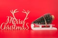 Christmas is coming concept. Close up photo of miniature christmas tree on little wooden sledge and merry chrismas wooden curved