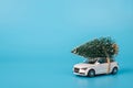 Christmas is coming concept. Close up side photo of toy mini car with little christmas tree on top isolated on blue background Royalty Free Stock Photo