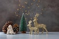 Christmas composition. Angel, pine cones, reindeer and Christmas tree on a white table and gray background with fairy lights Royalty Free Stock Photo