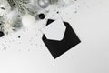 Christmas composition, black envelope, white and silver decorations, fir tree branches, silver stars confetti on white background. Royalty Free Stock Photo