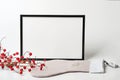 Christmas composition. Black frame and christmas sock with branches with red berries on white background.