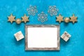 Christmas composition. Blank photo frame mockup, gift boxes, golden stars, balls and snowflakes. Turquoise blue grunge background