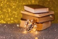 Christmas composition. Books, garland and pine cone on a gold background. Copy space.