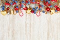 Christmas composition border flat lay top view. Red holly berries, blue berries, golden stars, garland, baubles and green fir Royalty Free Stock Photo