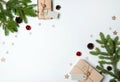 The border is made of gift boxes, fir branches, pine cones, red bells, wooden decorative snowflakes and stars on a white backgroun Royalty Free Stock Photo