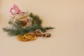 Christmas composition. Branches of spruce, dried orange circles in a glass jar with candy canes on a light beige background