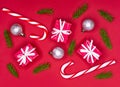Christmas composition. Christmas decorations, fir tree branches, giftboxes and candycanes on red background. Flat lay. Royalty Free Stock Photo