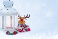 Christmas composition - deer, lantern with a burning candle and decorations under the Christmas tree Royalty Free Stock Photo