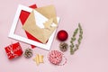 Christmas composition. Envelope with blank white paper, fir branches, cones, red ball, twine, gift, wooden toys on pink background
