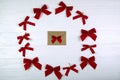 Christmas composition. Envelope in the center of the bows on wooden white background. Flat lay, top view.