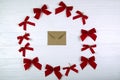 Christmas composition. Envelope in the center of the bows on wooden white background. Flat lay, top view.