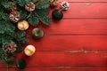 Christmas composition. Christmas fir tree branches with pine cones and papers rustic balls on wooden red rustic background. Royalty Free Stock Photo