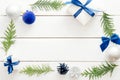 Christmas composition. Frame made of fir tree branches, blue decorations, gift boxes, cones, balls on white wooden background. Royalty Free Stock Photo