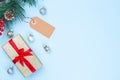 Christmas composition with gift box, pine branch, empty shopping tag and festive balls, on blue background, horizontal, copy space Royalty Free Stock Photo