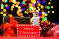 Christmas composition with a gift box, spruce cone, tinsel, and blurred lights in the background Royalty Free Stock Photo