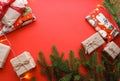 Christmas composition with gift boxes, clews of rope, paper`s rools and decorations, fir tree branches on red background.