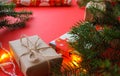 Christmas composition with gift boxes, clews of rope, paper`s rools and decorations, fir tree branches on red background.