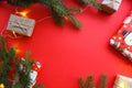 Christmas composition with gift boxes, clews of rope, paper`s rools and decorations, fir tree branches on red background.