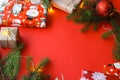 Christmas composition with gift boxes, clews of rope, paper`s rools and decorations, fir tree branches on red background.