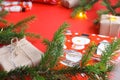 Christmas composition with gift boxes, clews of rope, paper`s rools and decorations, fir tree branches on red background.