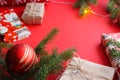 Christmas composition with gift boxes, clews of rope, paper`s rools and decorations, fir tree branches on red background.