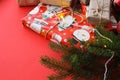 Christmas composition with gift boxes, clews of rope, paper`s rools and decorations, fir tree branches on red background.