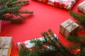 Christmas composition with gift boxes, clews of rope, paper`s rools and decorations, fir tree branches on red background.