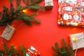 Christmas composition with gift boxes, clews of rope, paper`s rools and decorations, fir tree branches on red background.