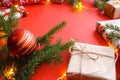 Christmas composition with gift boxes, clews of rope, paper`s rools and decorations, fir tree branches on red background.