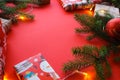 Christmas composition with gift boxes, clews of rope, paper`s rools and decorations, fir tree branches on red background.