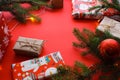 Christmas composition with gift boxes, clews of rope, paper`s rools and decorations, fir tree branches on red background.