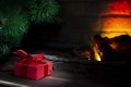 Christmas composition, gift under the tree near a burning fireplace, close-up Royalty Free Stock Photo