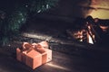 Christmas composition, gift under the tree near a burning fireplace, close-up Royalty Free Stock Photo