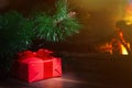 Christmas composition, gift under the tree near a burning fireplace, close-up Royalty Free Stock Photo