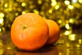 Christmas composition on gold bokeh background. Mandarins against a background of blurry defocused glittering lights and tinsel.