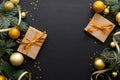 Christmas composition. Golden baubles, modern festive decorations, gift boxes, fir tree branches on dark black background. Elegant