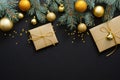 Christmas composition. Golden baubles, modern festive decorations, gift boxes, fir tree branches on dark black background. Elegant Royalty Free Stock Photo