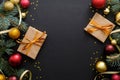 Christmas composition. Golden and red balls, modern festive decorations, gift boxes, fir tree branches on dark black background.