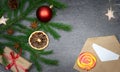 Christmas composition on a gray background with a fir branch, candy, a cone, dried orange and star anise, an envelope